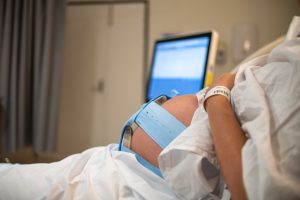 A woman laying in a hospital bed going into labor while connected to a monitor.