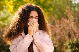 A woman blowing her nose due to seasonal allergies.